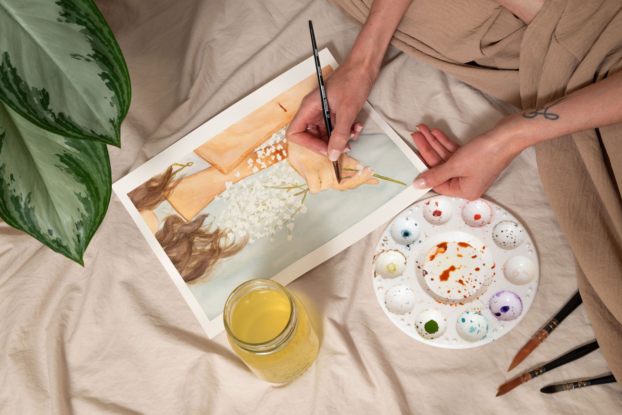 Close up Artiste aquarelle peignant mains sur fond beige avec plantes